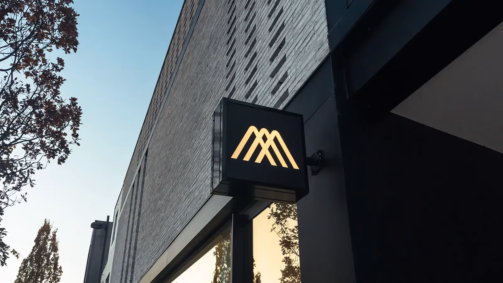 Stijlvolle zwarte buitenlamp tegen een moderne bakstenen gevel in de avondschemering.