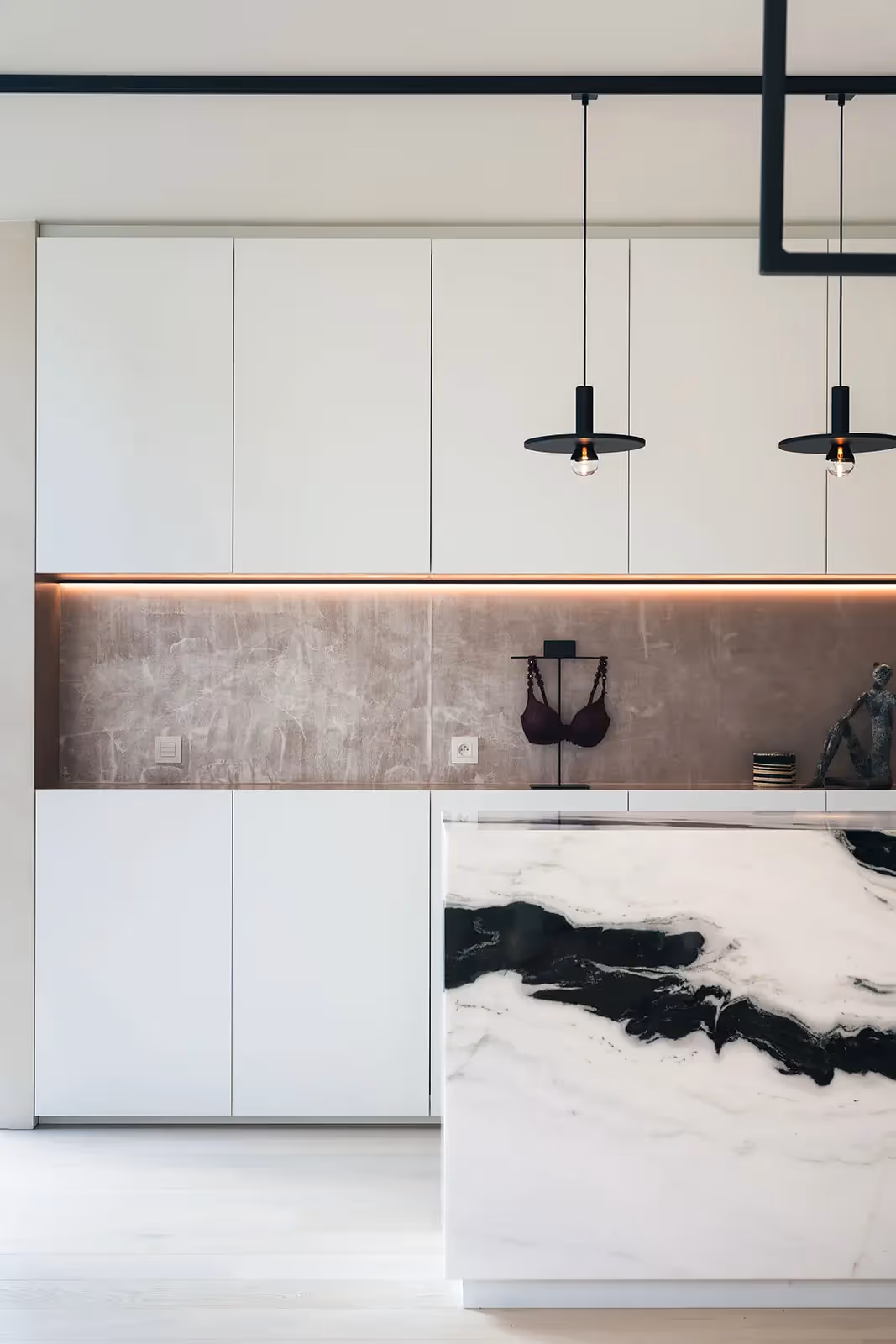Moderne keuken met witte kasten, zwart-wit marmeren werkblad en hanglampen.