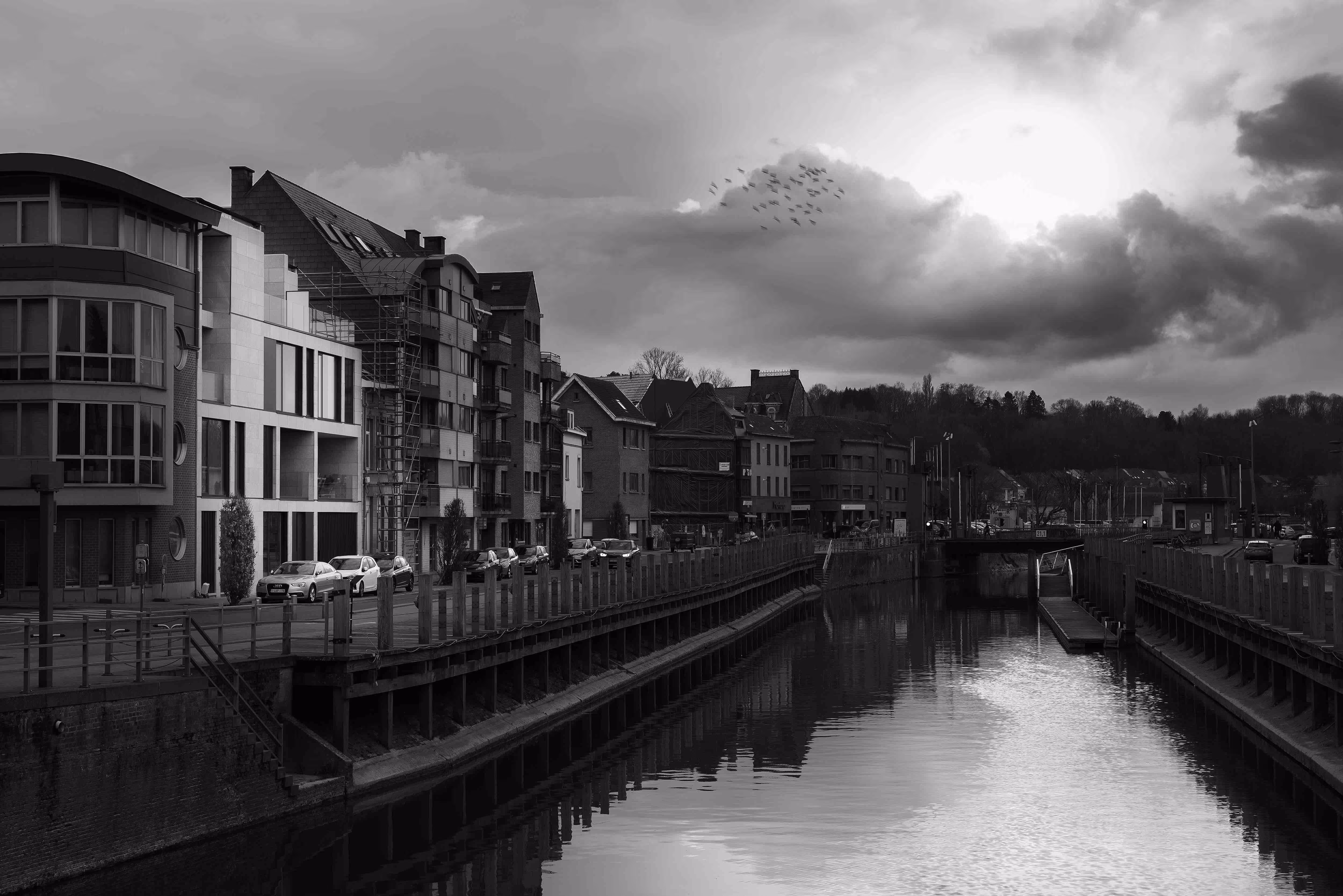 Moderne stadsarchitectuur met een combinatie van traditionele en hedendaagse gevels langs een kanaal, met mensen die voorbijwandelen.