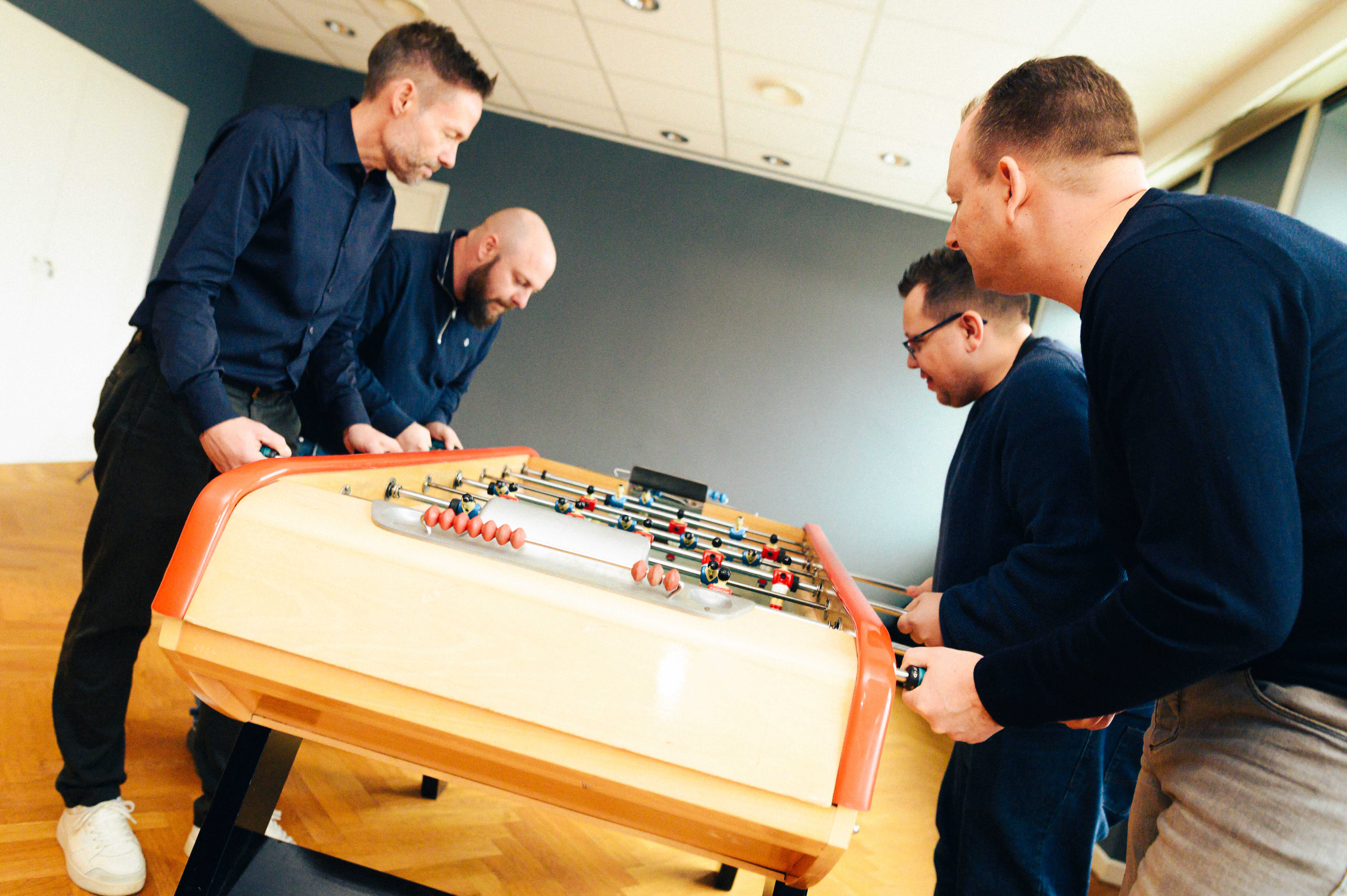 Mindkey-medarbejdere der spiller bordfodbold på kontoret – en del af kulturen hos Mindkey HR-software.
