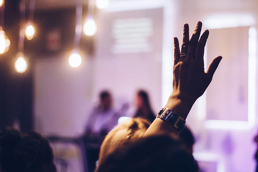 person raising their hand at a conference