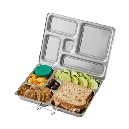 Open stainless steel compartmentalized lunch box with whole wheat bread, cucumber slices, cheese, crackers, and green lid container