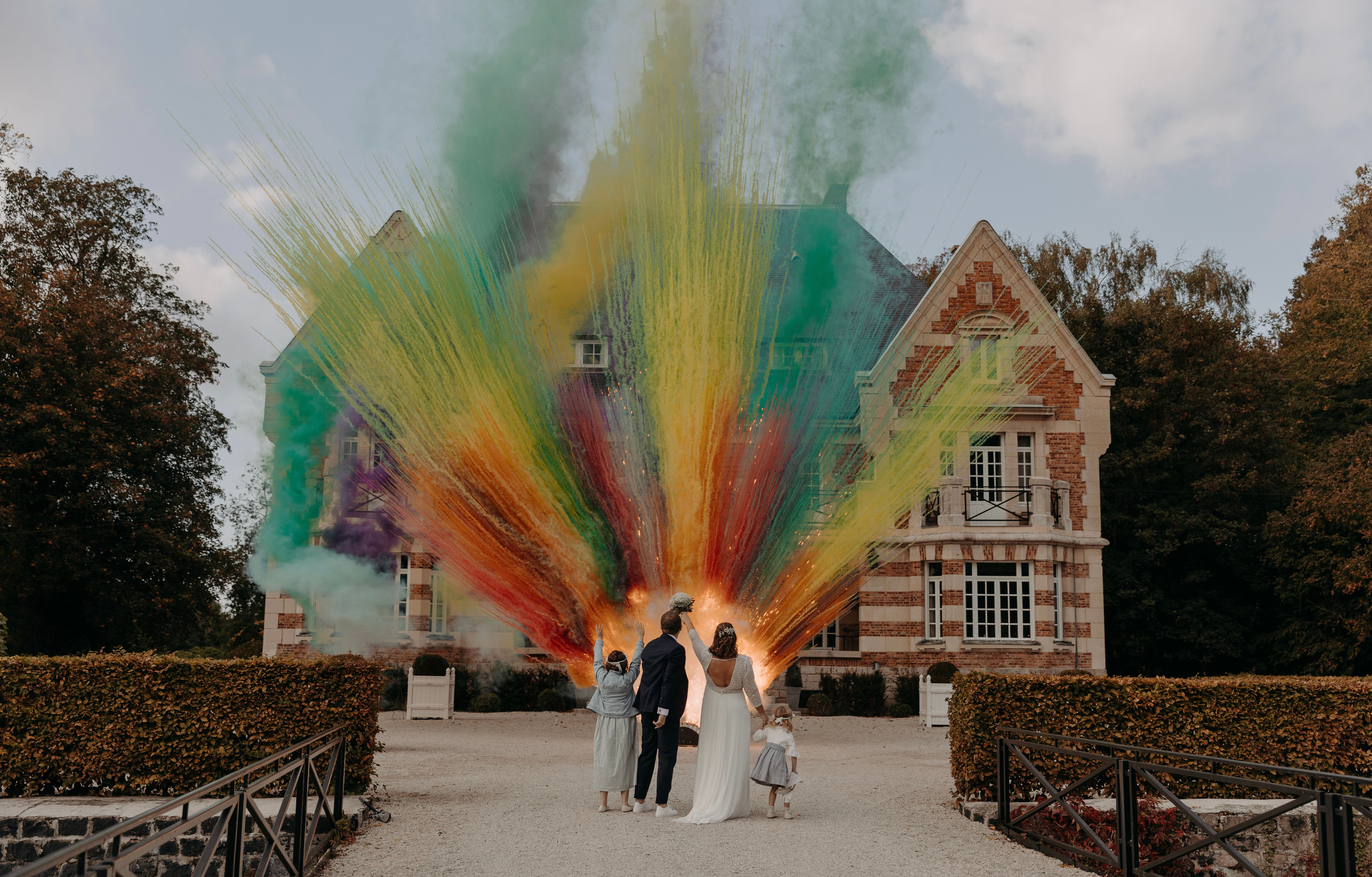 Mariés et enfants admirant le feu d'artifice de jour multicolores devant un château lors de leurs mariage