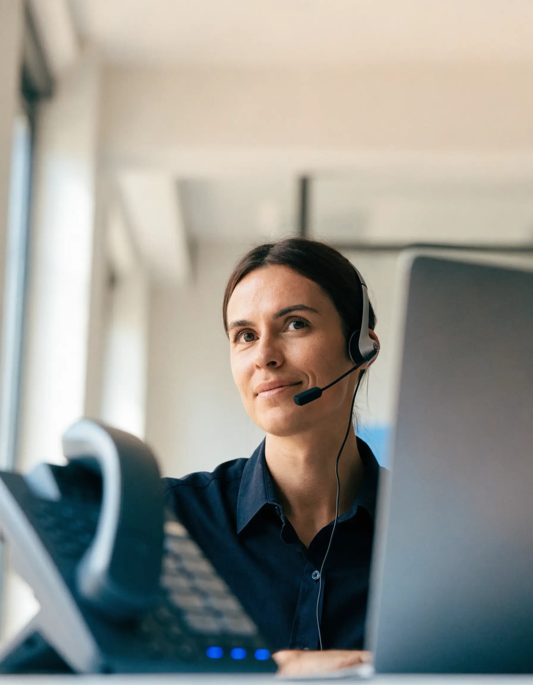 Mitarbeiterin mit Headset telefoniert über die Cloud-Telefonanlage im Büro