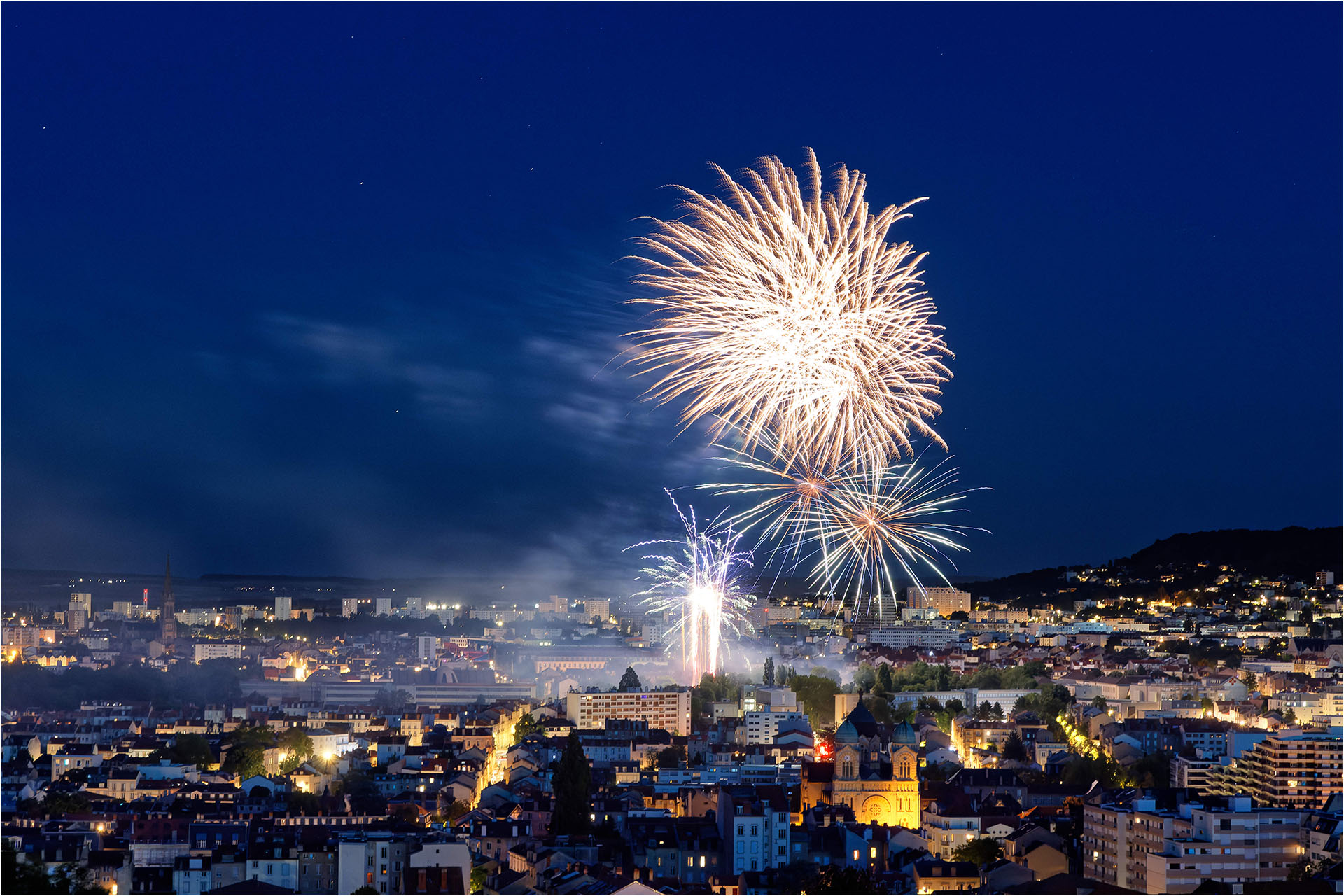 Feux d'artifice explosant au-dessus des bâtiments illuminés de Nancy lors d'un spectacle pyrotechnique nocturne