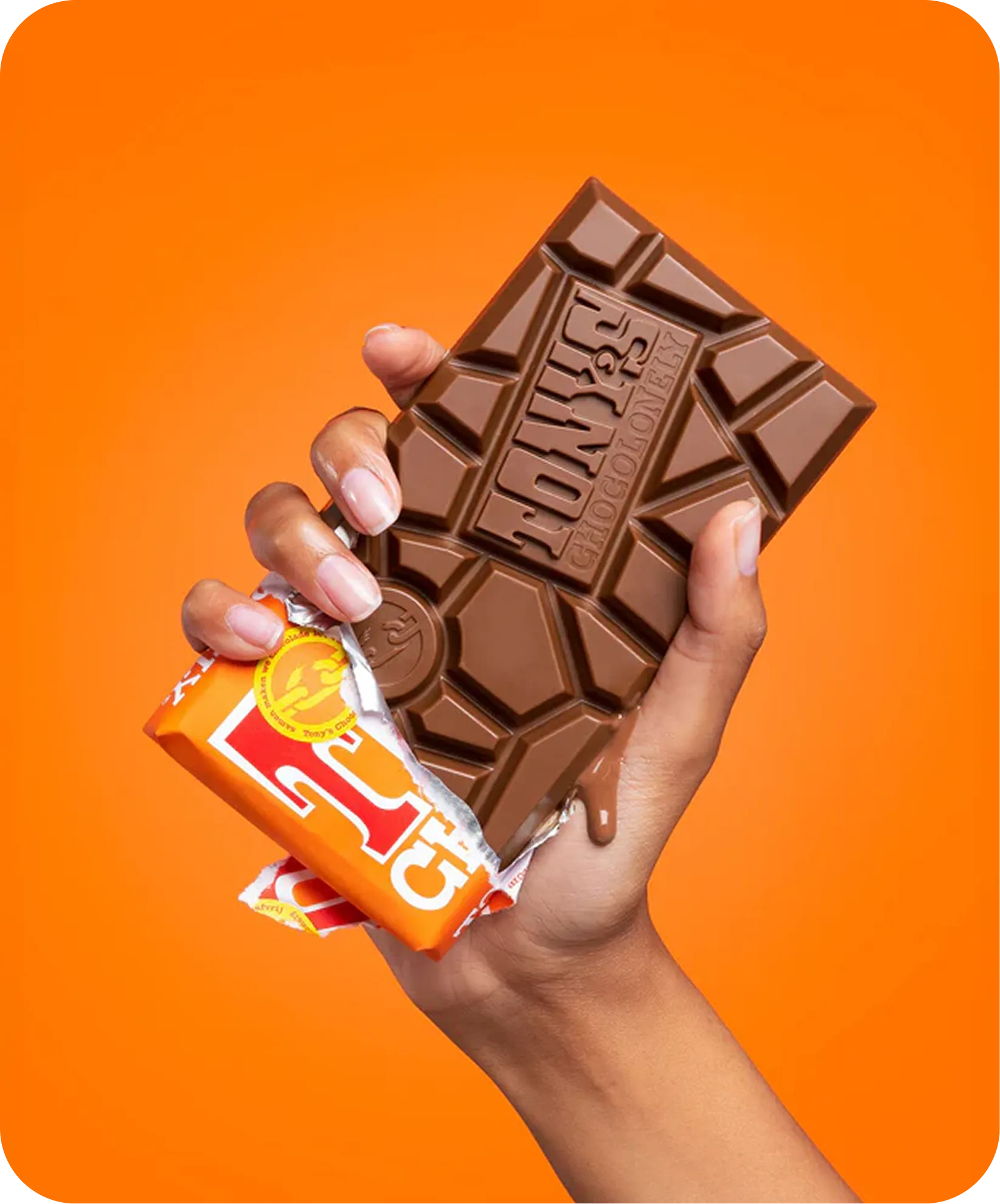Hand holding a melting Tony's Chocolonely chocolate bar partially wrapped in orange packaging.