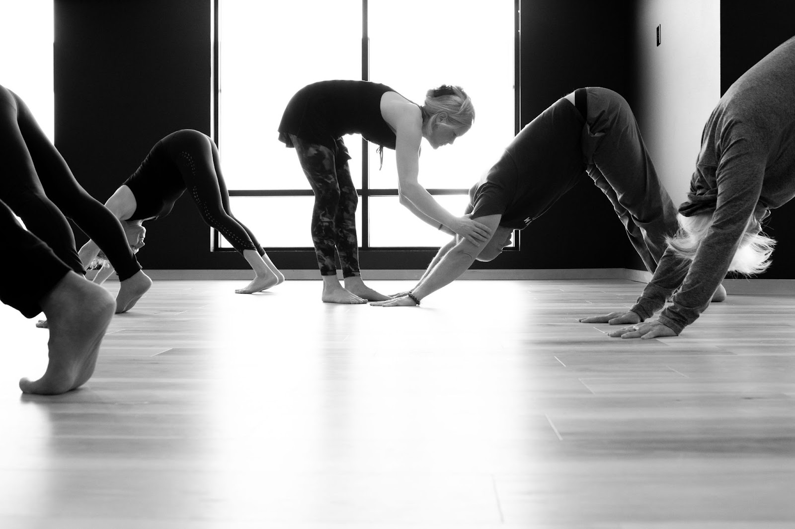 teacher adjusting a student in downward dog