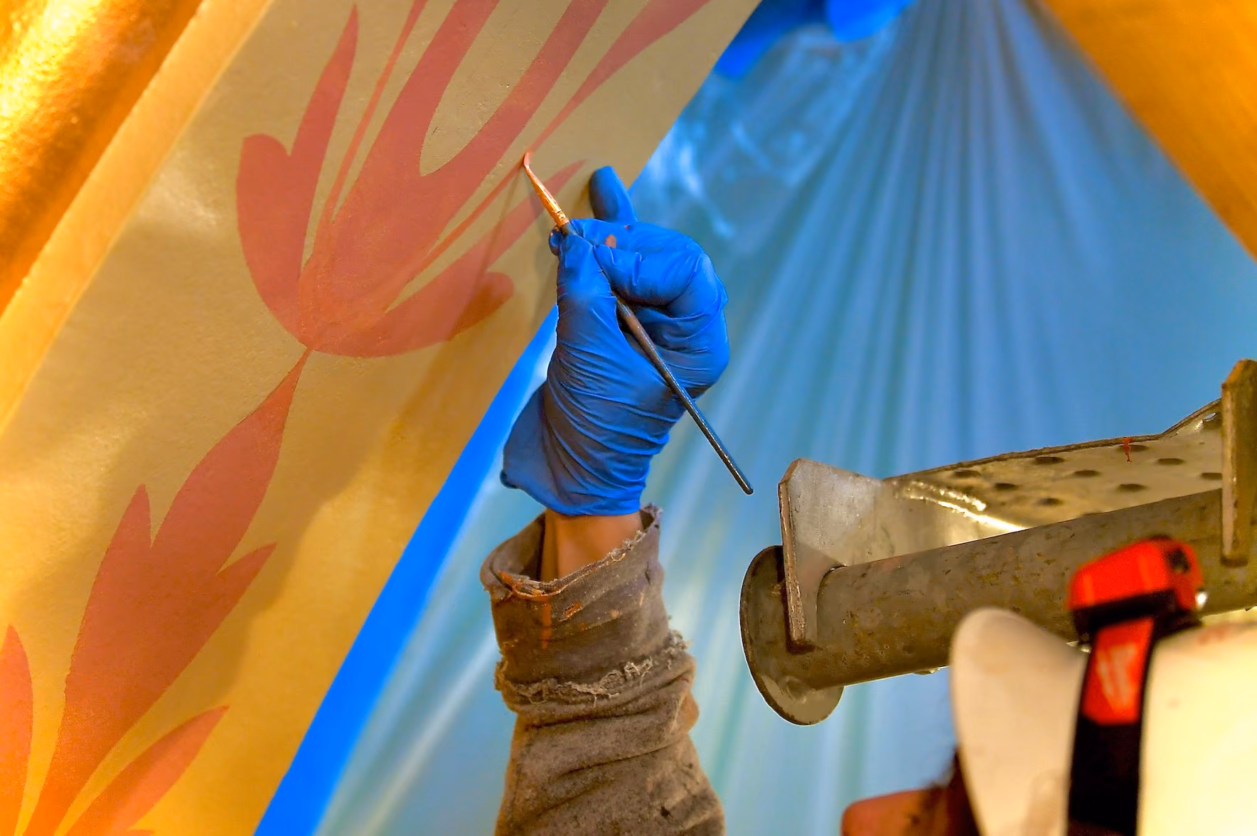 Photo of person restoring a painting using a fine brush and wearing magnifying goggles