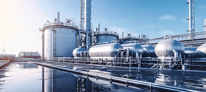 Industrielle Anlage mit großen silbernen Tanks und Rohrleitungen unter klarem Himmel.