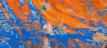 Abgeblätterte orange und blaue Farbe auf rauer Holzoberfläche.
