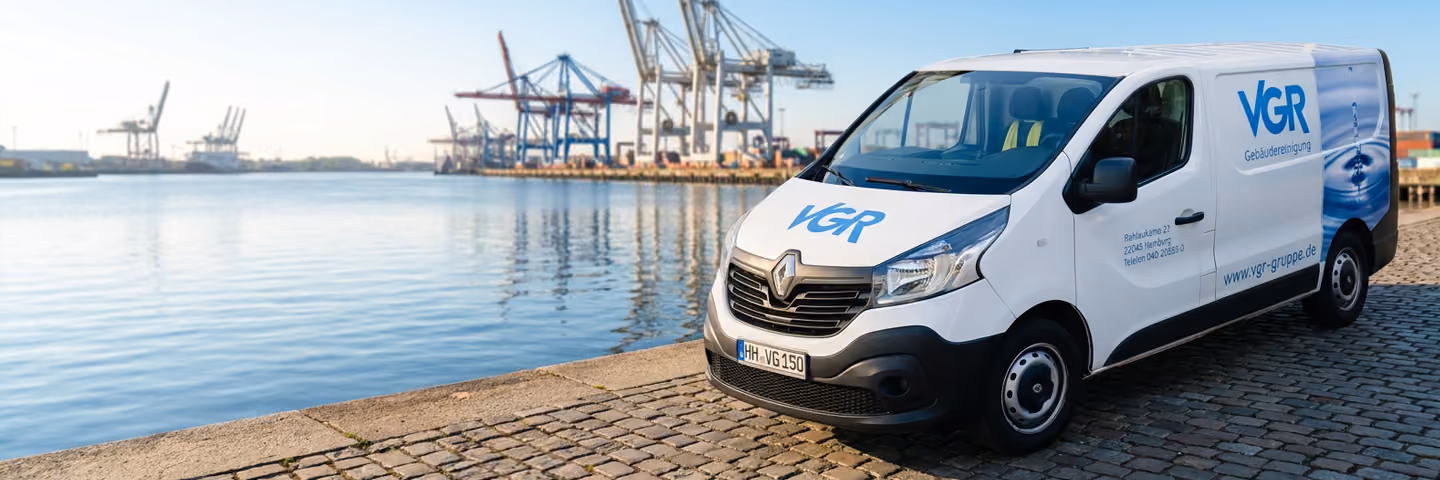 Ein weißer Lieferwagen mit dem Schriftzug VGR und Kontaktdaten steht a, Hamburger Hafen mit Krananlagen am Wasser.
