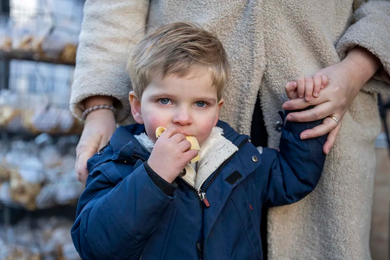 Schattig jongetje eet een stukje kaas voor de marktkraam van Peter Kastelein van Daalder kaas.