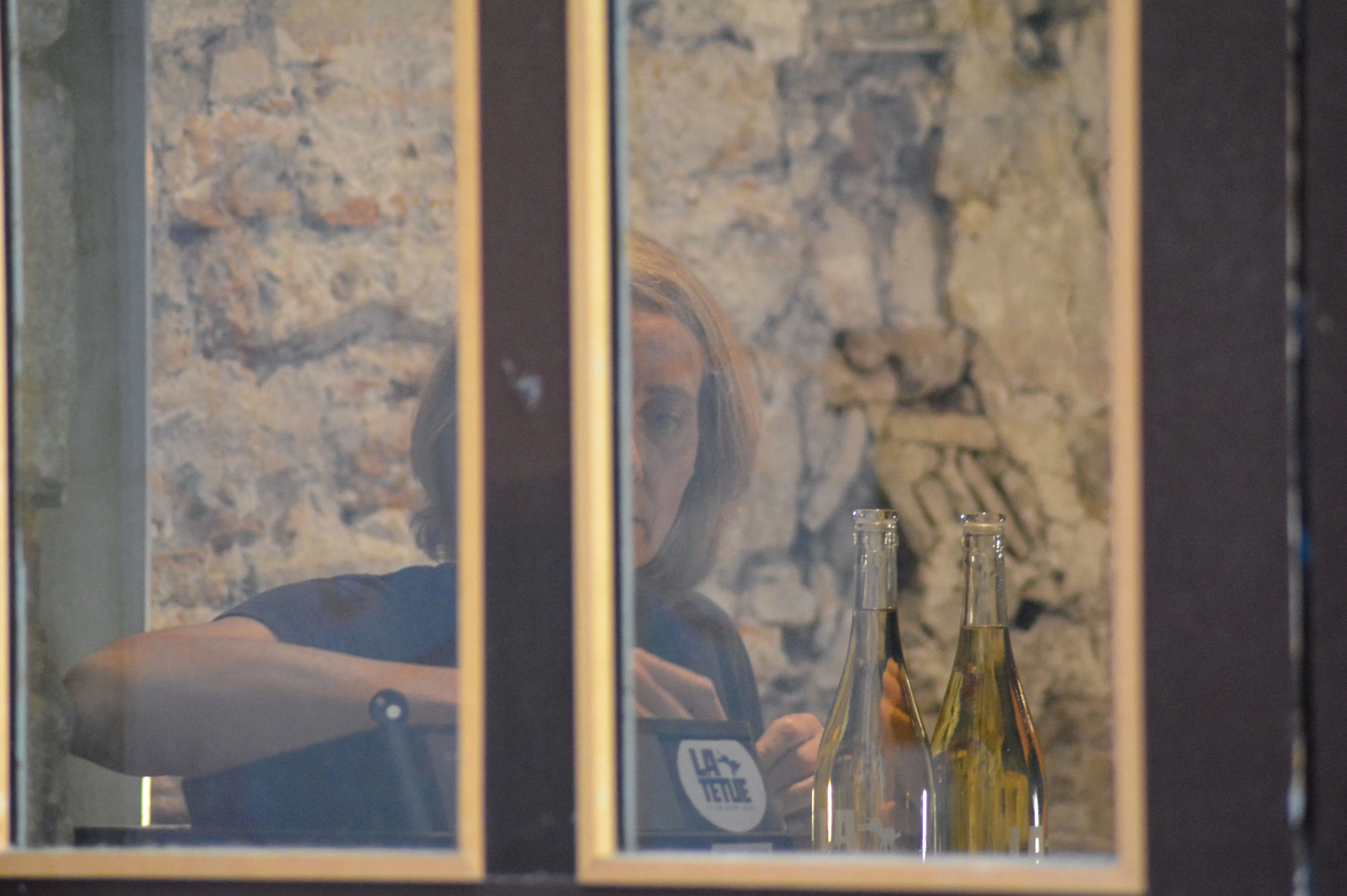 Géraldine à la caisse de la cave La Têtue - vue de l'extérieur à la fenêtre