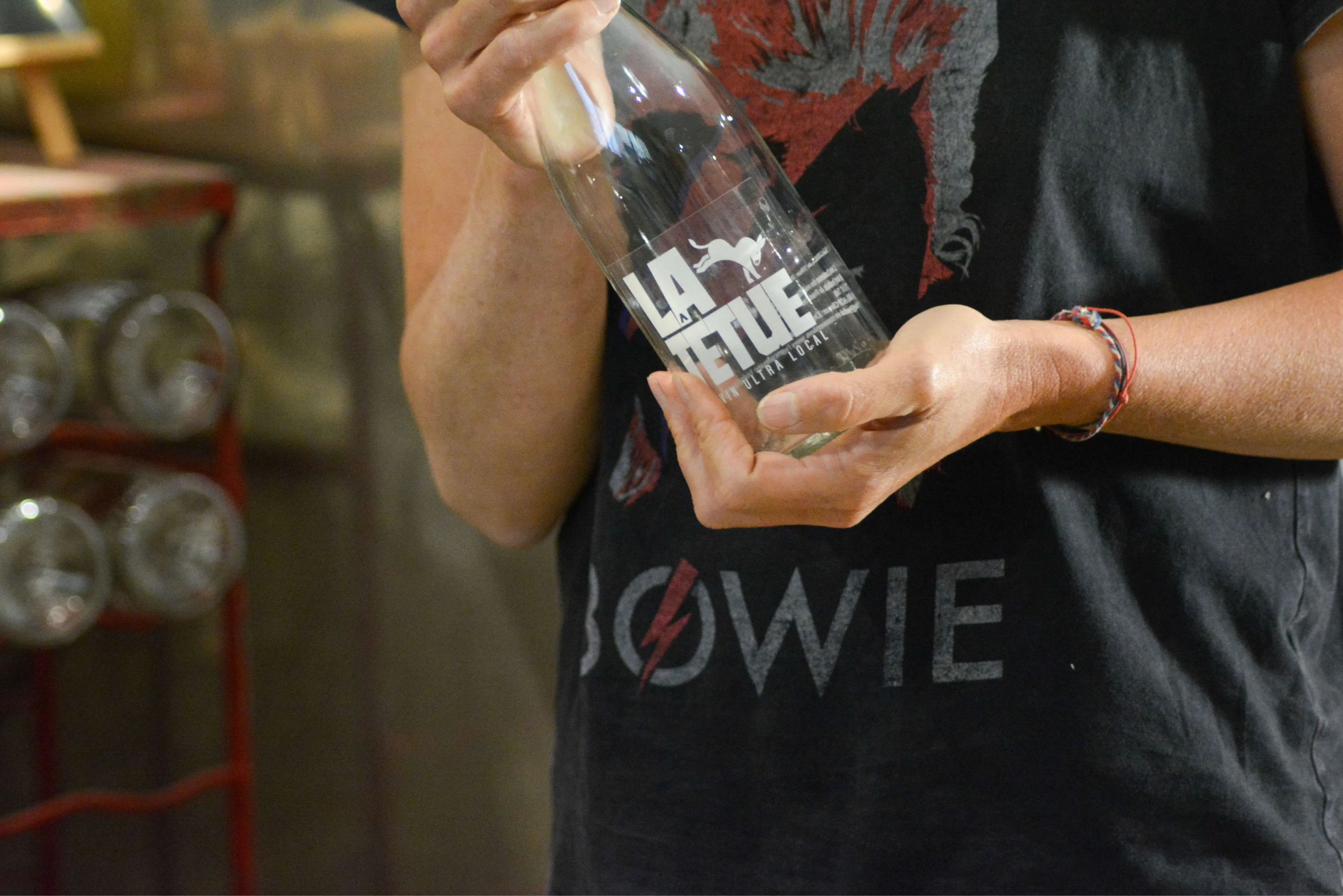 Bouteille de vin nature La Têtue avec logo tenue dans les mains de Géraldine