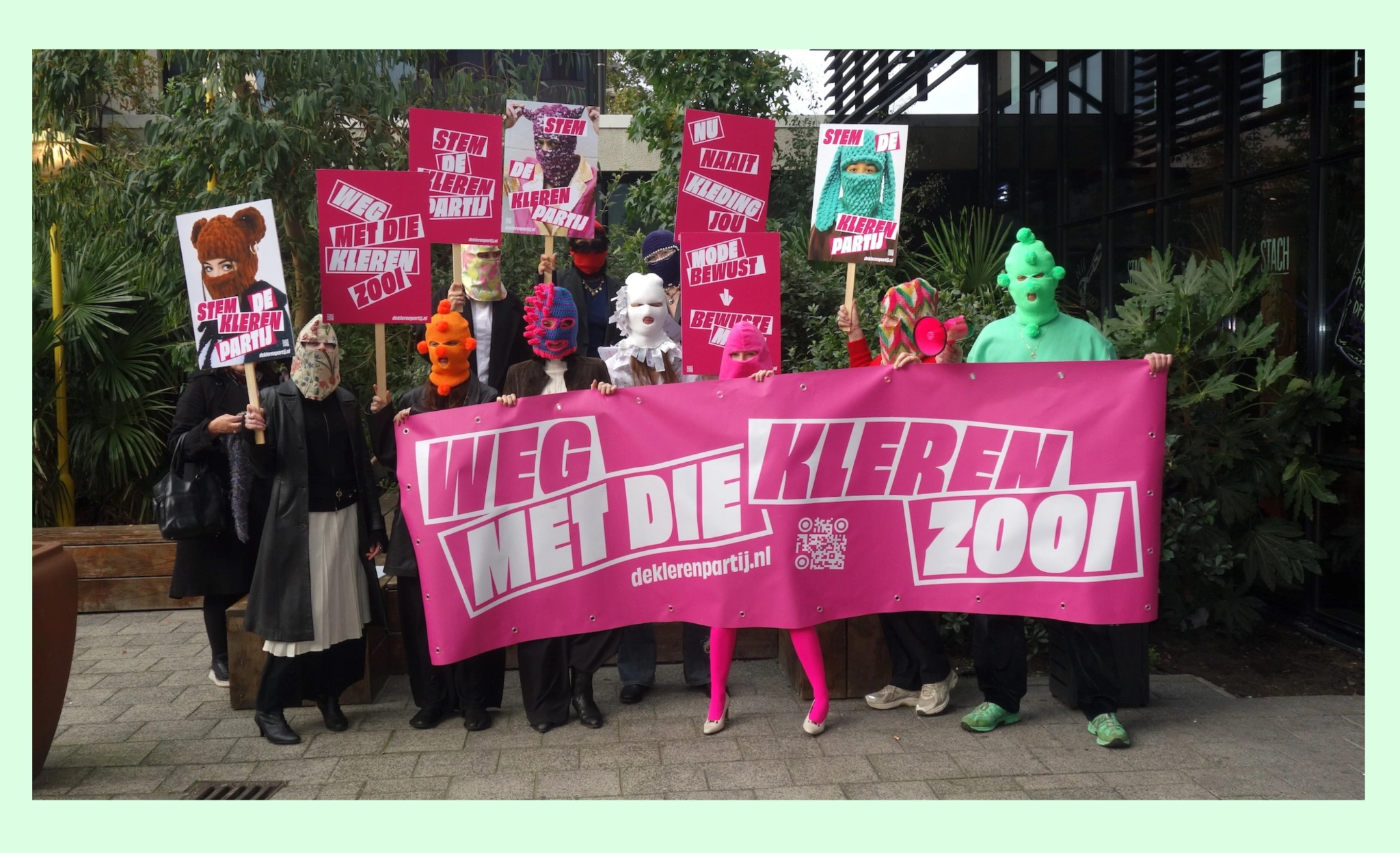 Militants masqués de De Klerenpartij brandissant la banderole rose « Weg met die kleren zooi » et des pancartes « Stem De Kleren Partij » devant l'hôtel de ville d'Arnhem, Pays-Bas, lors d'une action pour inscrire le vêtement circulaire à l'agenda politique.