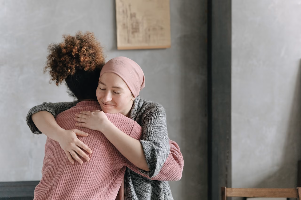 Female undergoing cancer treatment, hugging a loved one.