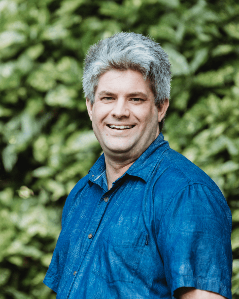 Shallow depth of field portrait of Dan Faulknor, against a green leafy backdrop.