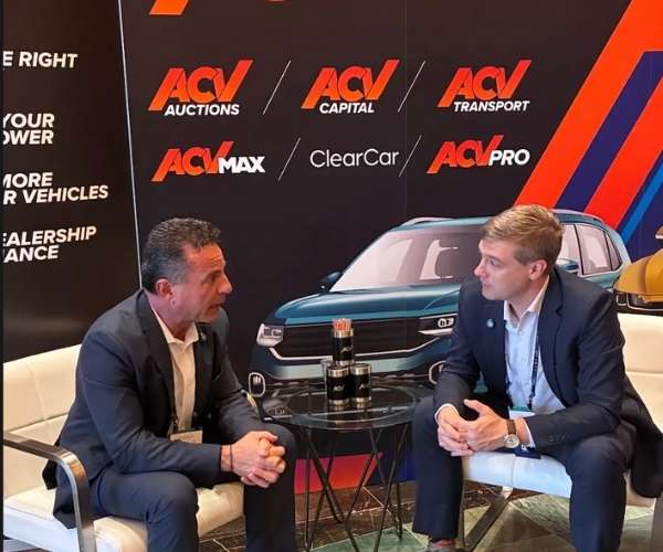 Two men in suits talk to each other at a conference