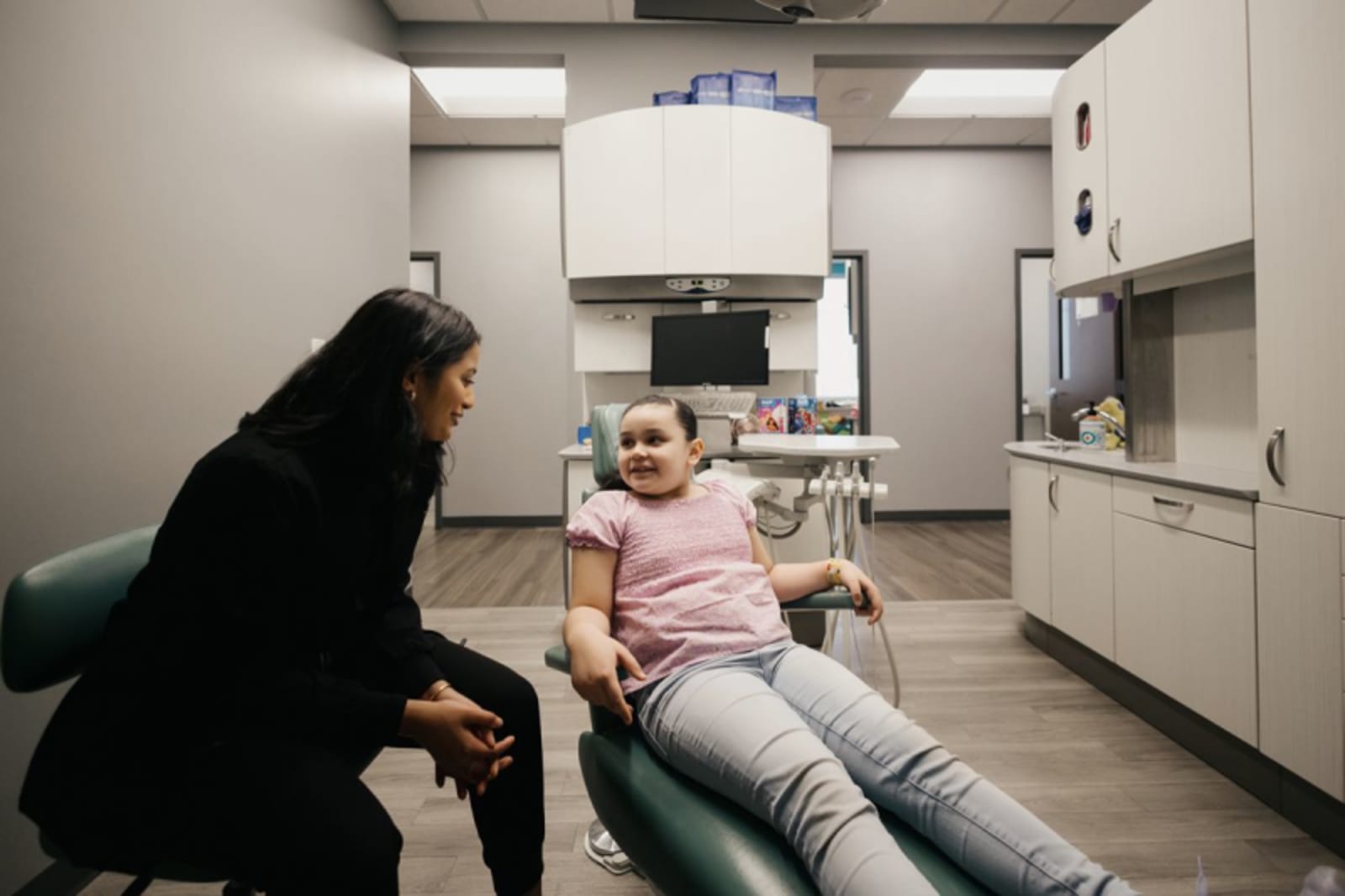 Dentist explaining dental crown procedure to a child in treatment room