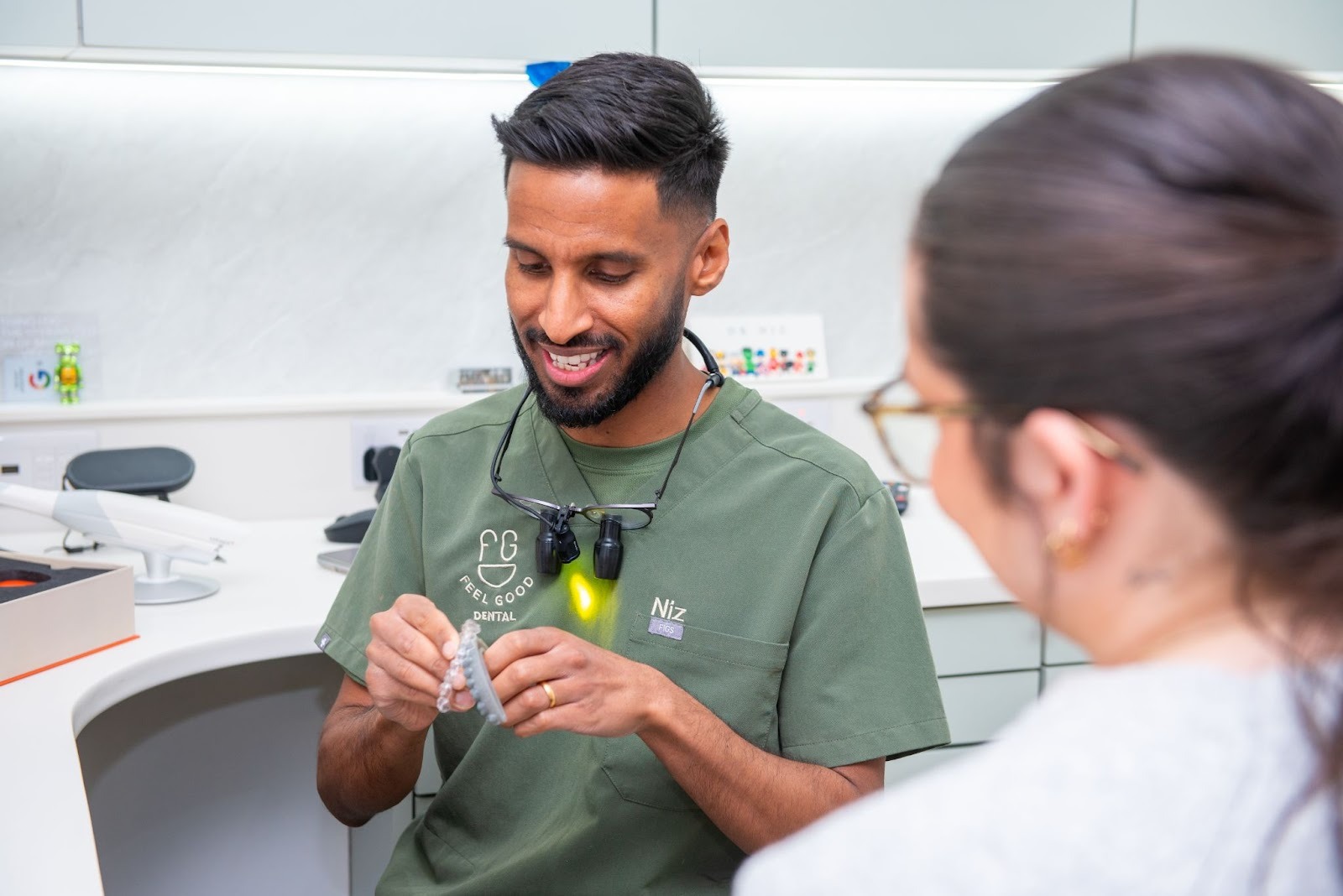 Croydon dentist Dr Niz from Feel Good Dental discussing Invisalign clear aligners with a patient during a consultation.
