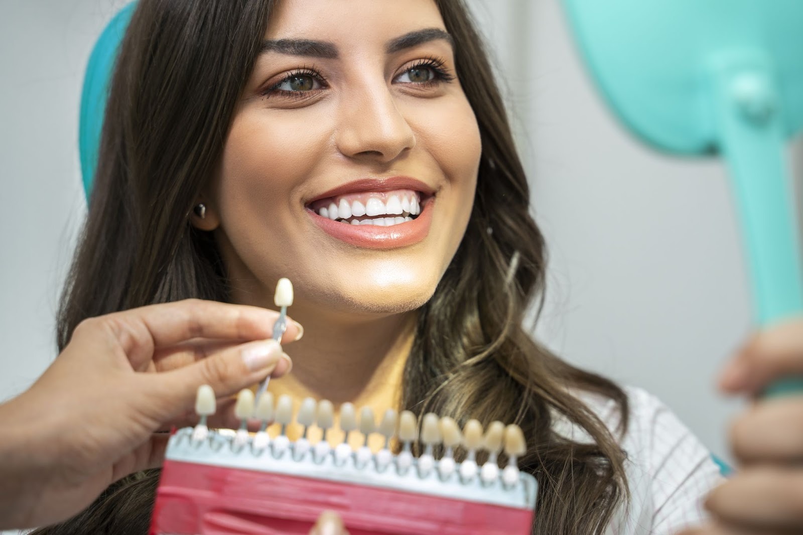 Woman comparing tooth shade samples during a professional teeth whitening consultation in Croydon