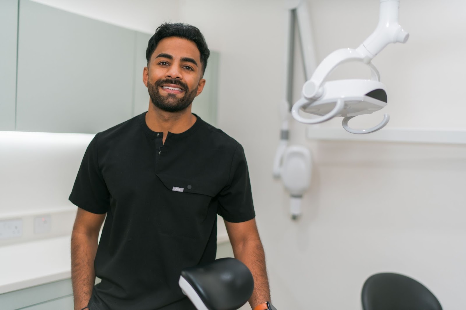 Dr Nev Jeyakumar, Implant dentist at Feel Good Dental in Croydon standing in a modern dental surgery, ready to guide patients through dental implant treatment