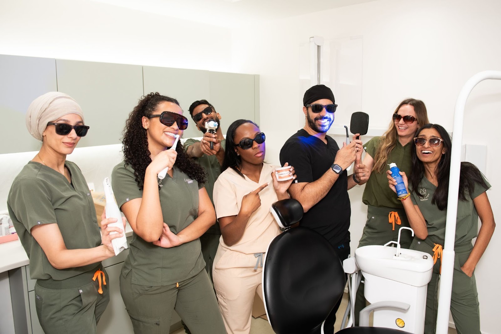 Feel Good Dental team in Croydon posing playfully with dental equipment to show a relaxed and friendly practice environment