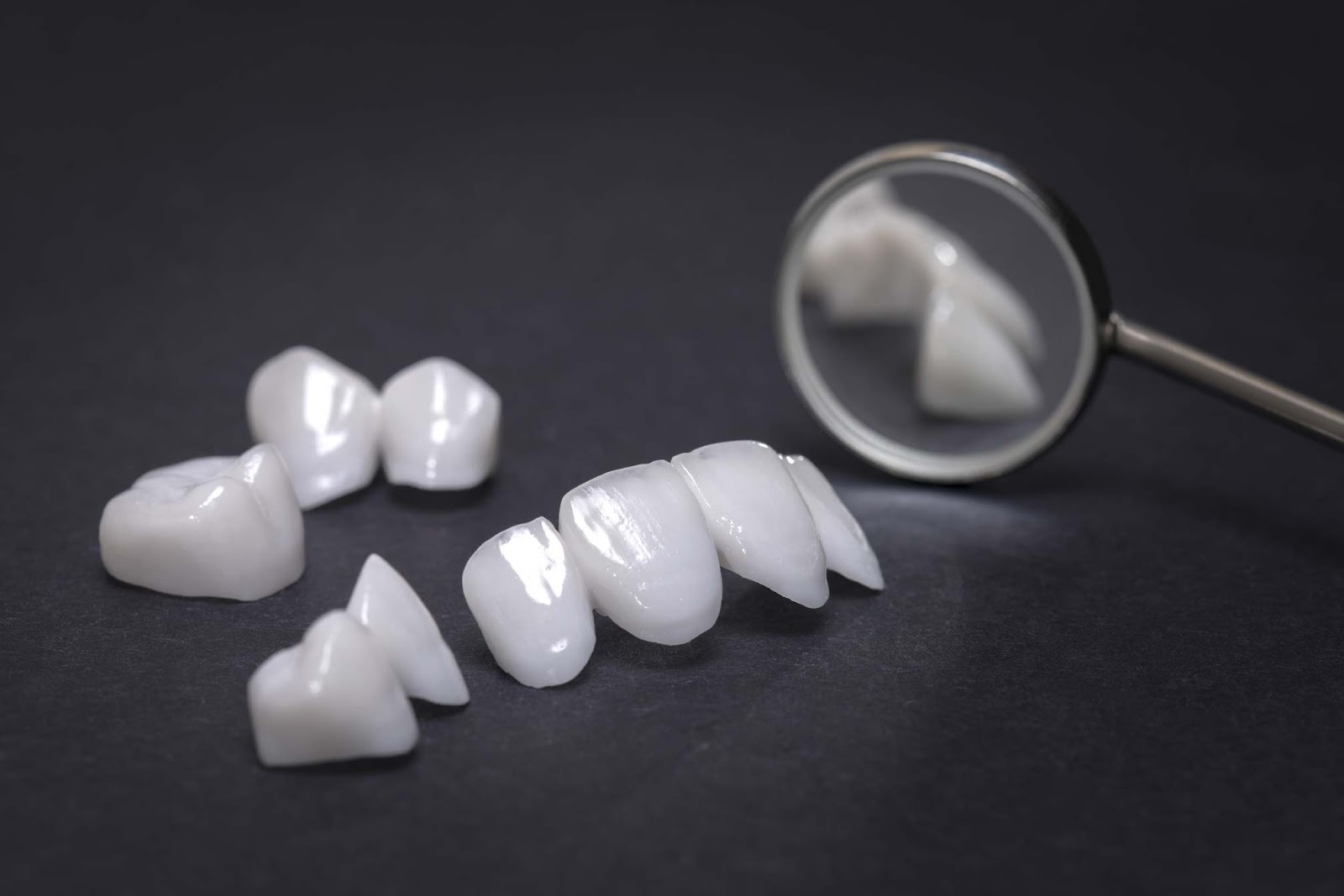 Ceramic dental crowns and bridge restoration displayed with dental mirror
