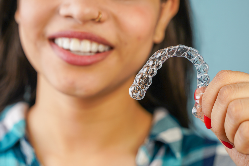 Patient holding a clear Invisalign aligner for teeth straightening