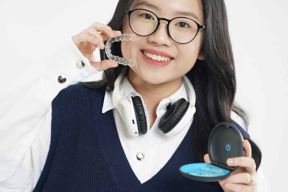Woman holding clear aligners and an aligner case