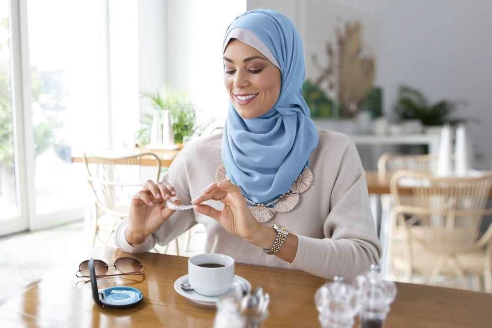 Woman with clear aligners and aligner case while having coffee