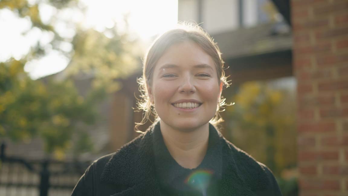 Happy woman smiling outside a South London dental practice after professional veneer treatment with Foxley Lane Dental, Purley.