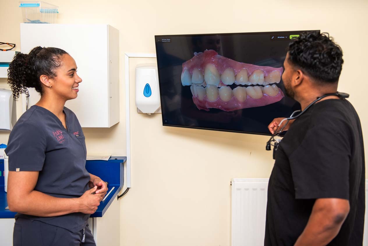 Dentist explaining a 3D digital model of teeth on a screen during cosmetic dental treatment planning