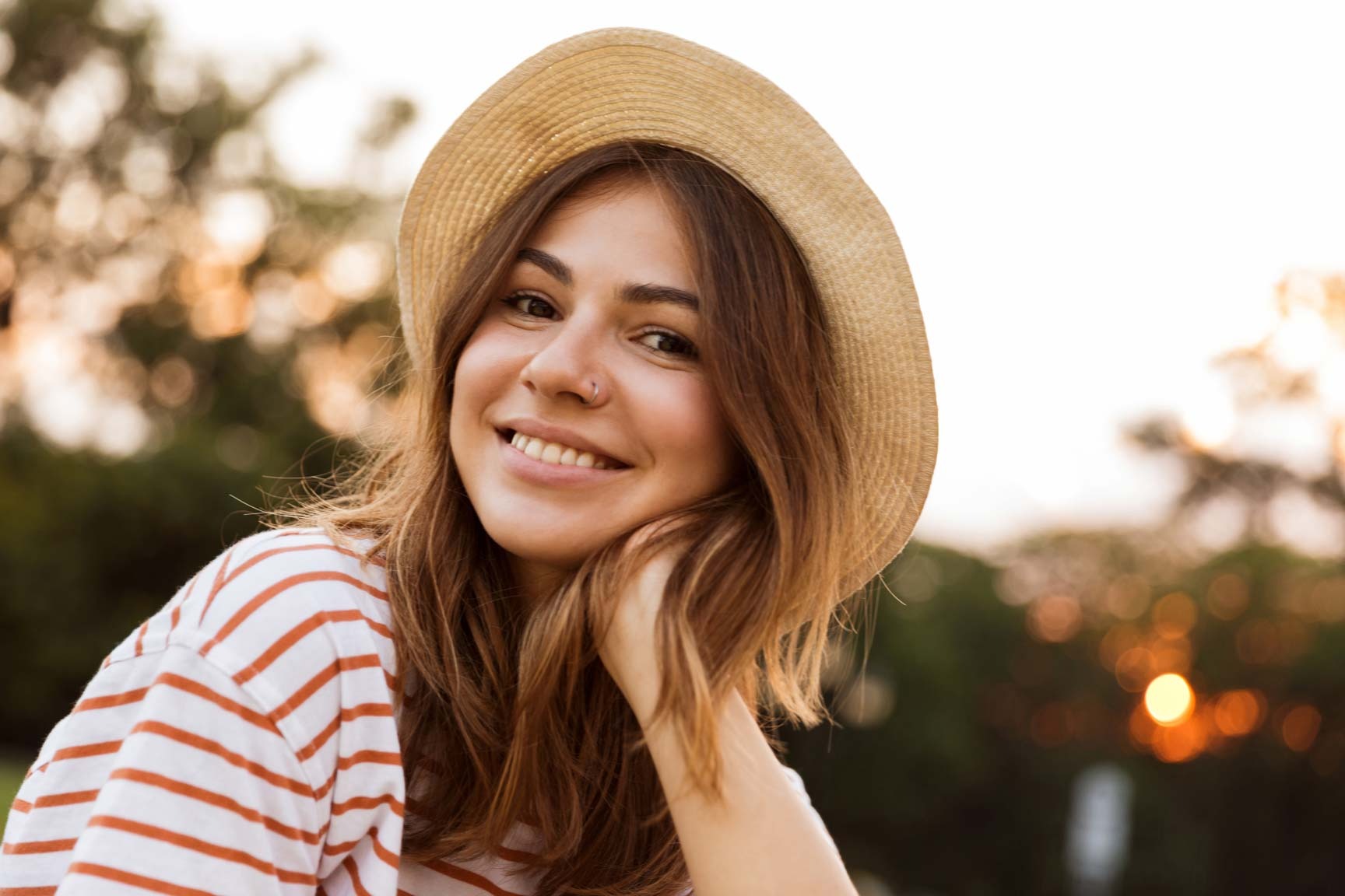 Young woman smiling outdoors with natural looking teeth after cosmetic dental treatment