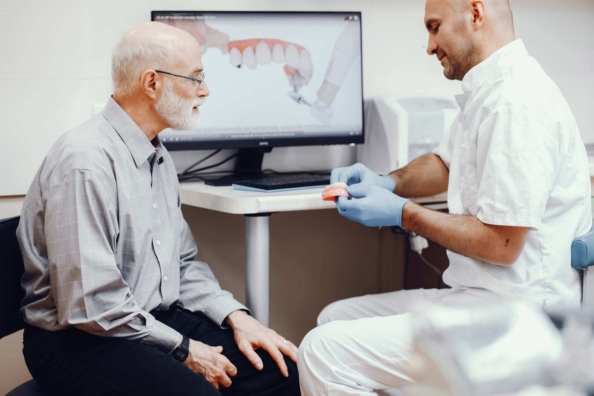 Dentist explaining tooth replacement options using a dental model during a consultation