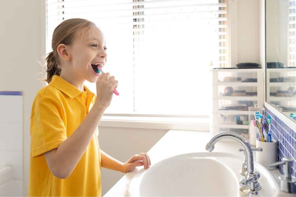 Young child brushing their teeth with fluoride toothpaste at home