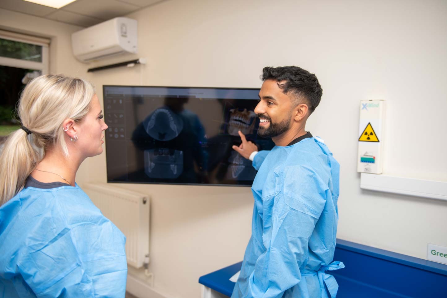 Dr Nev Jeyakumar, implant dentist, going over a dental scan with a patient at an implant consultation at Foxley Lane Dental in Purley