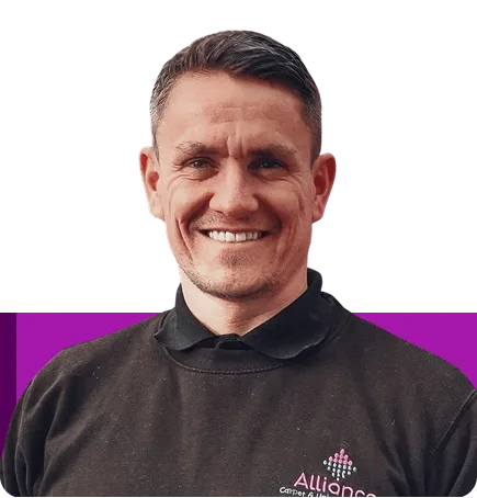 Smiling man with short dark hair wearing a black Alliance branded sweater.