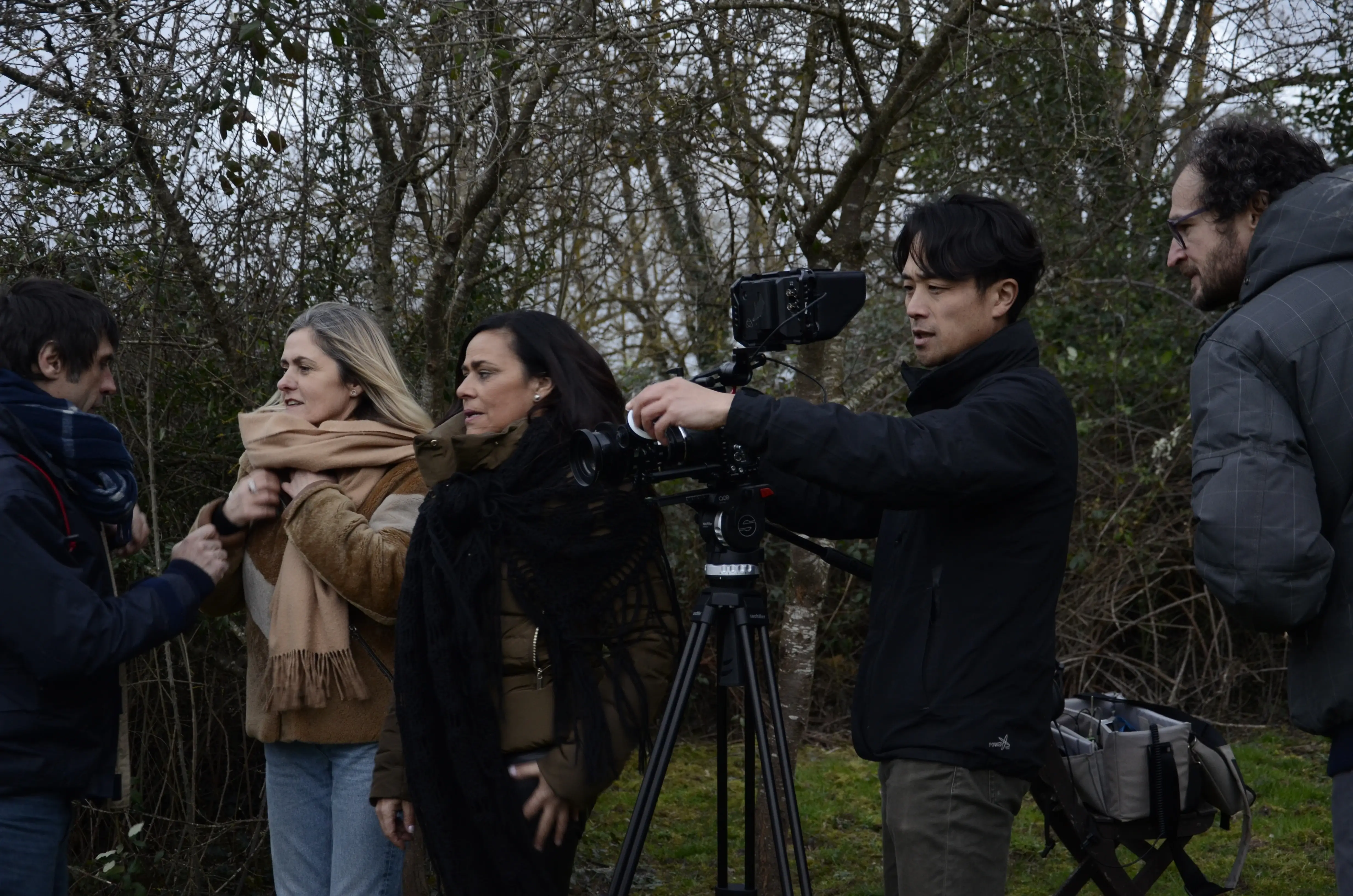 Cinq personnes en extérieur, une filme avec une caméra sur trépied, en forêt en arrière-plan.