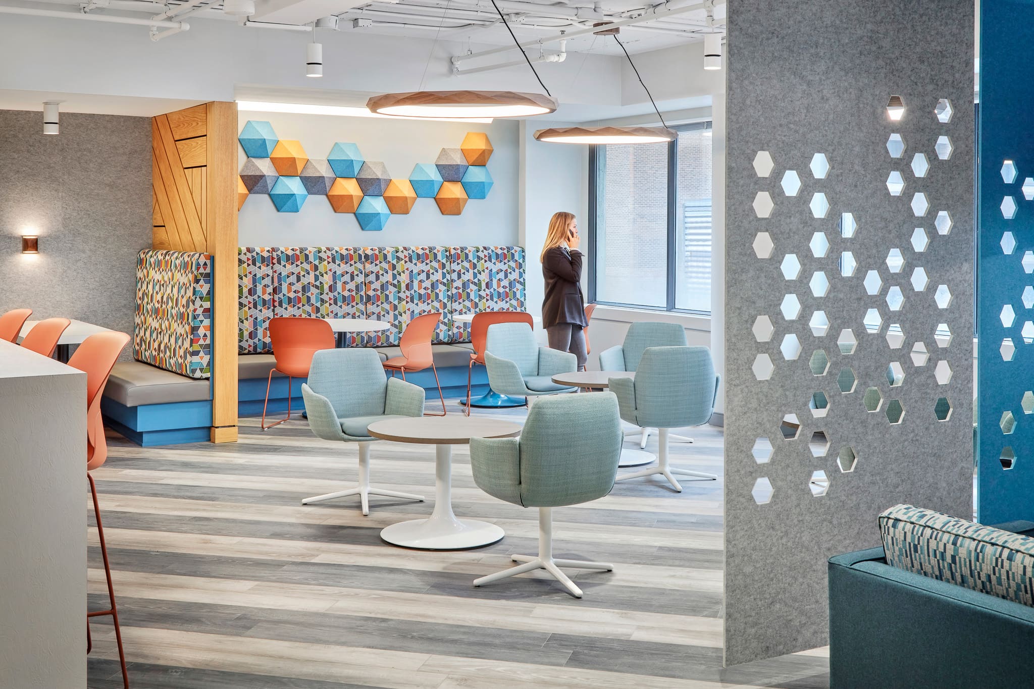 Bright and open interior modern office space featuring various seating area, neutral wood and colourful accents. 