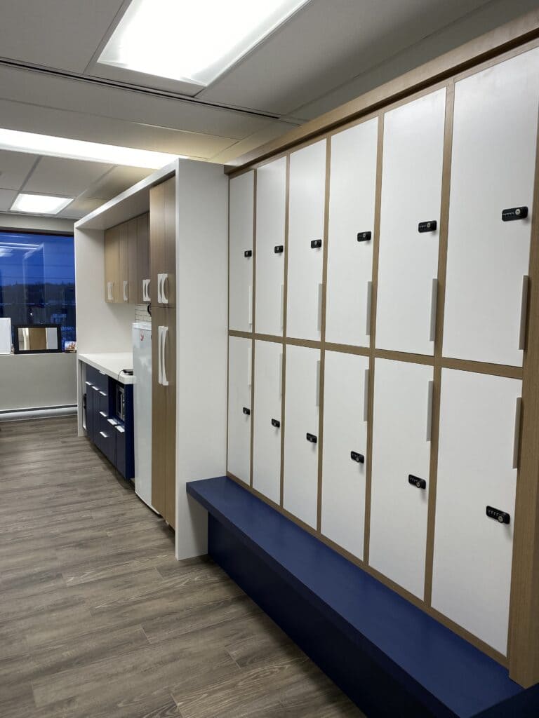 Locker room featuring lockers, a bench, and a kitchenette with a fridge. 