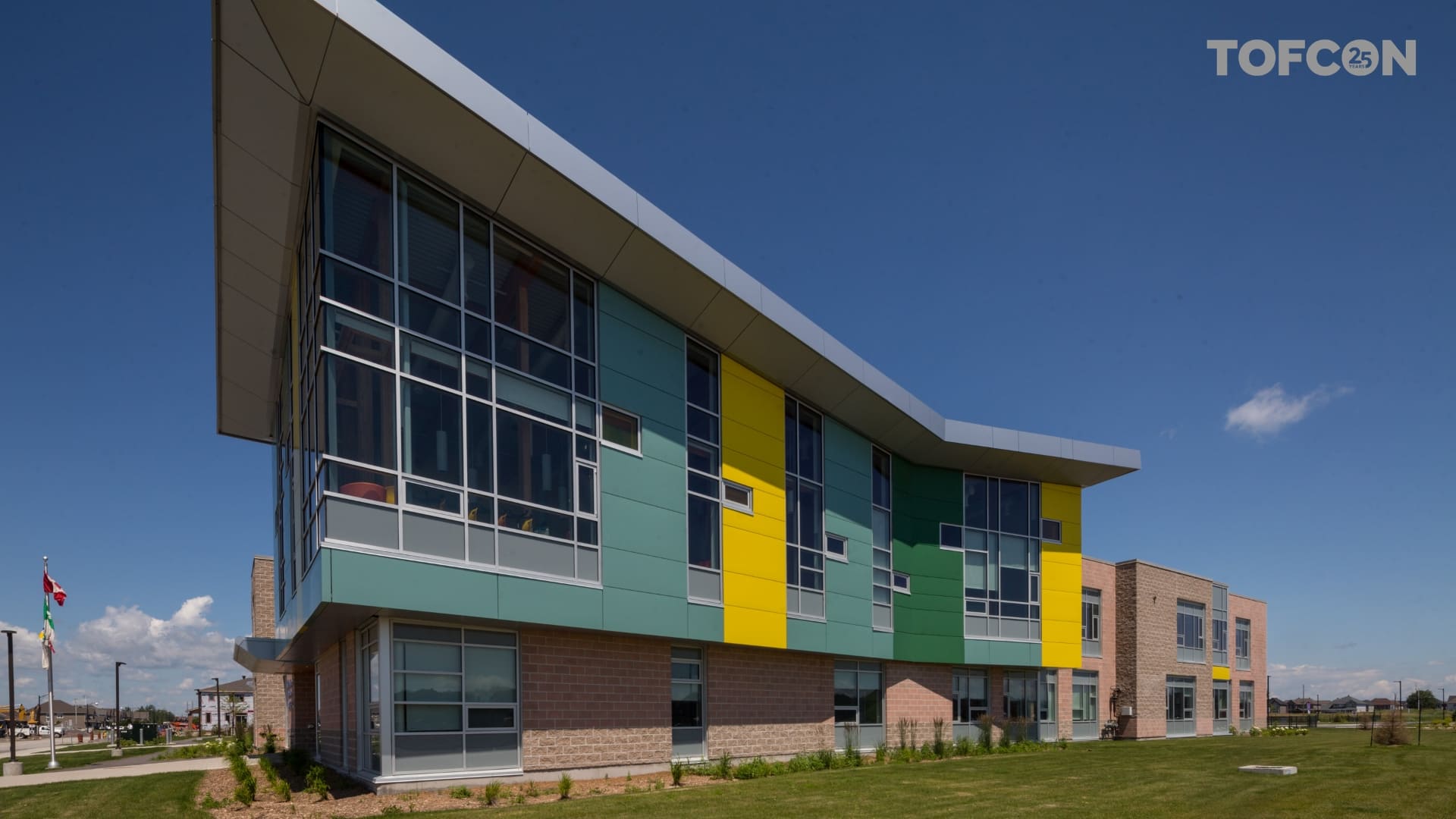  Exterior of Ecole Notre Place, featuring a base brick building and modern colourful with large windows. 