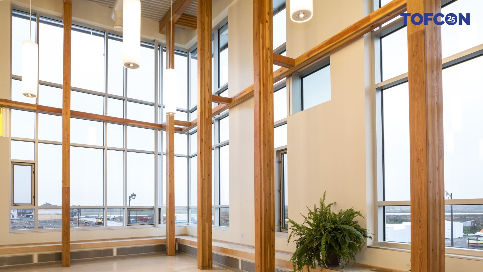 Interior of Notre Place École featuring tall wood beams from floor to ceiling in front of large windows. 