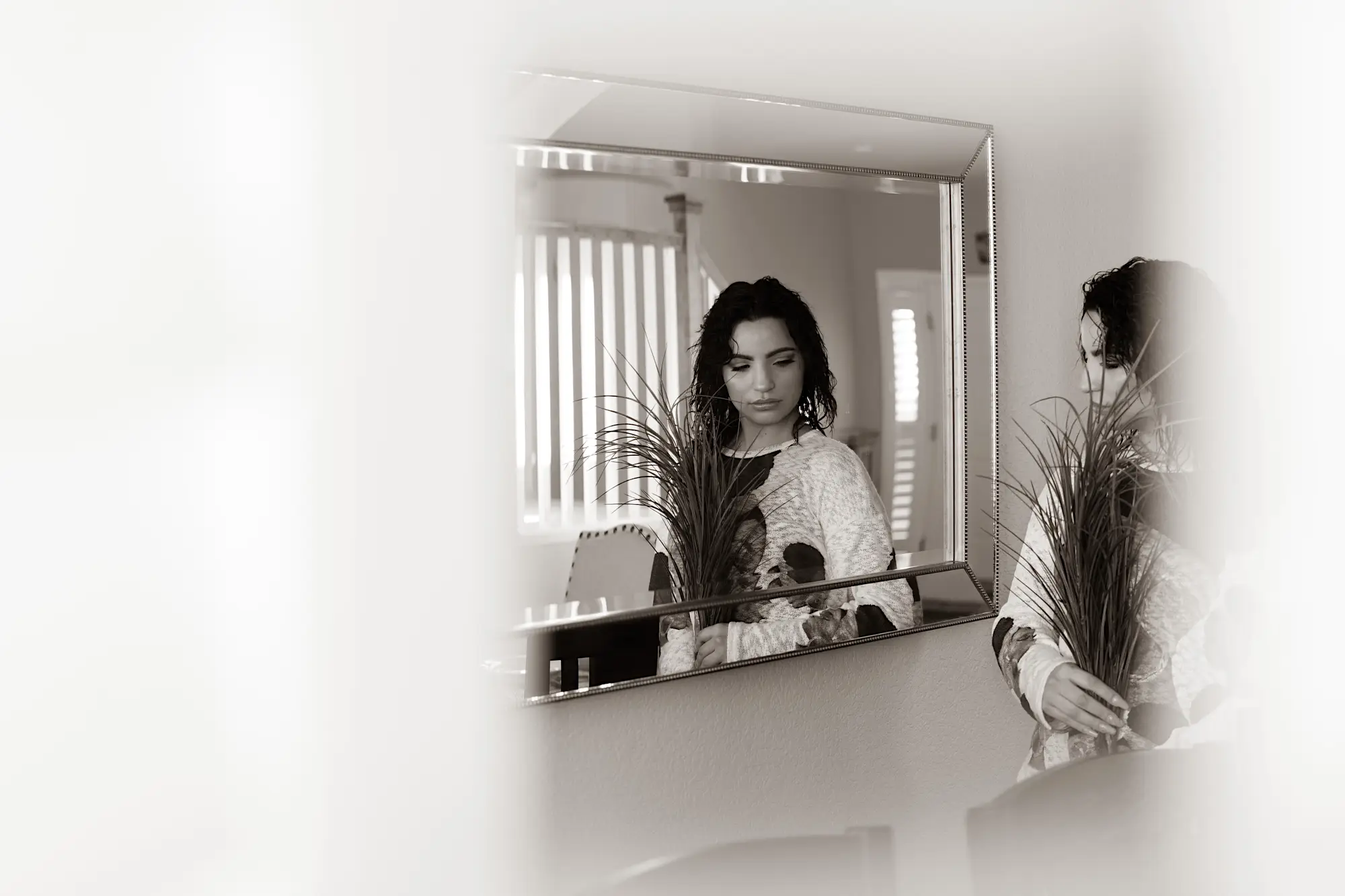 Woman holding flowers looking at herself in a mirror