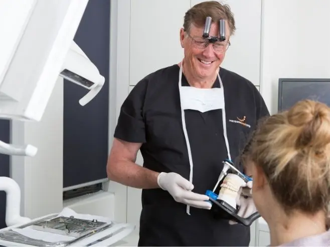 Dr David Dunn shows a model of an all-on-4 bridge to a patient at Macquarie Street Dental.