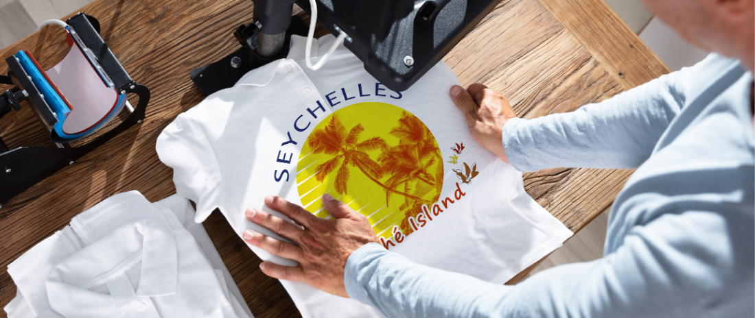 Person bedruckt mit einer Heißpresse ein weißes T-Shirt mit einem tropischen Design und einem Schriftzug
