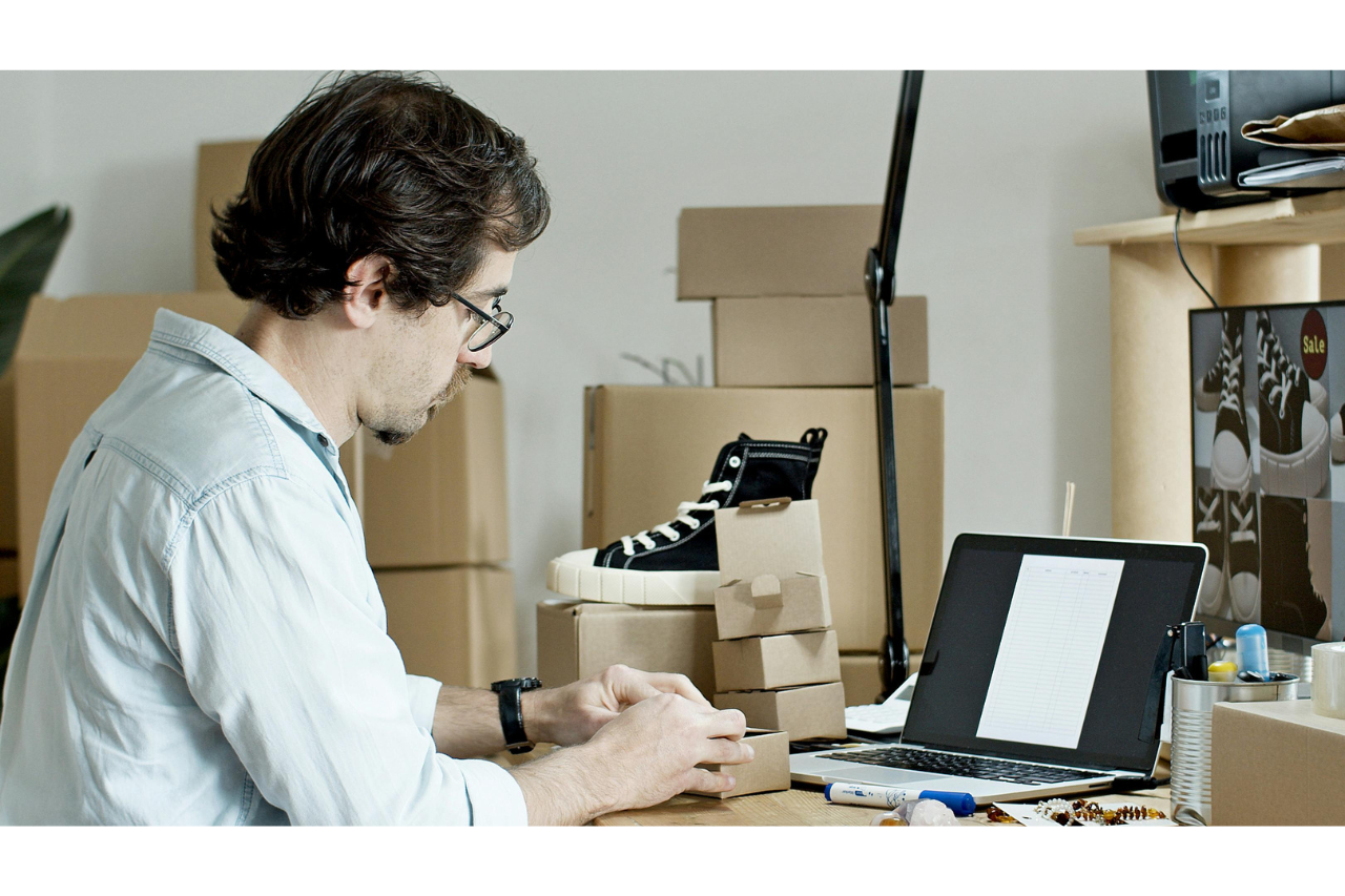 Mann sitzt am Schreibtisch und arbeitet am Laptop an seinem Shopify Shop