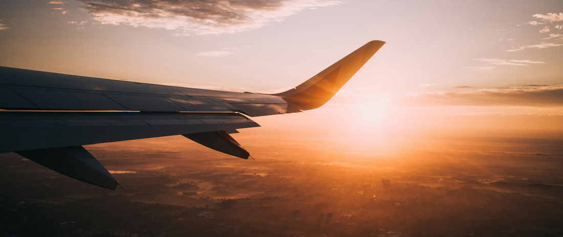 Flugzeugflügel bei Sonnenuntergang – Symbolbild für Dienstreise und Reisekosten absetzen