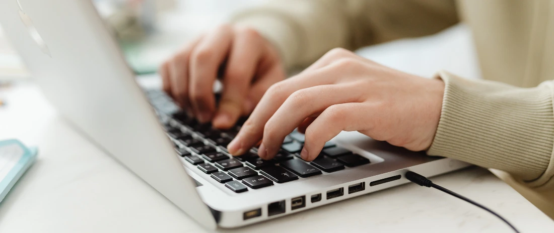 Person am Laptop, die nach dem besten Rechnungsprogramm für Kleinunternehmer sucht