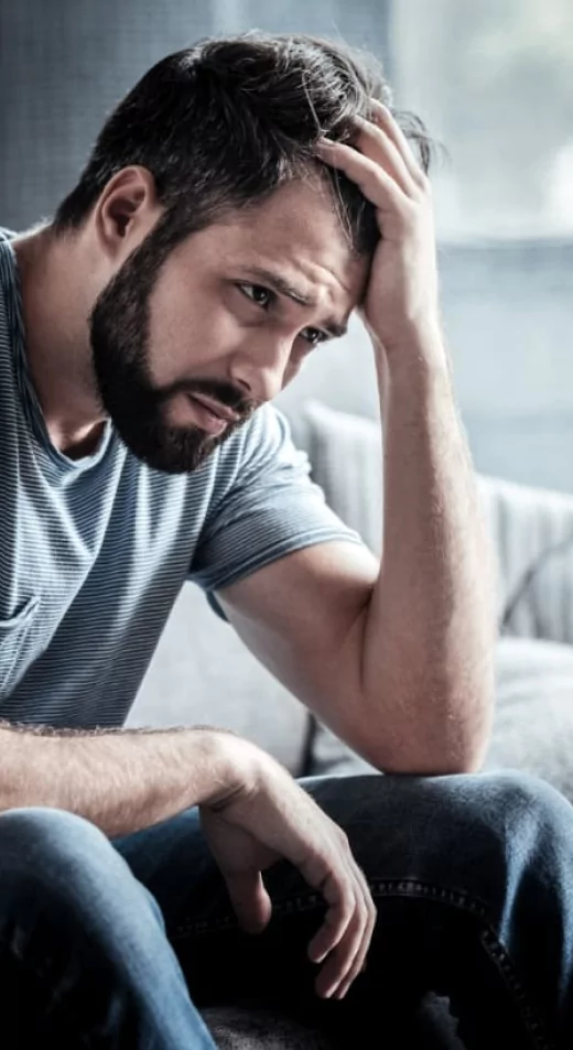 a man sitting on a couch holding his head